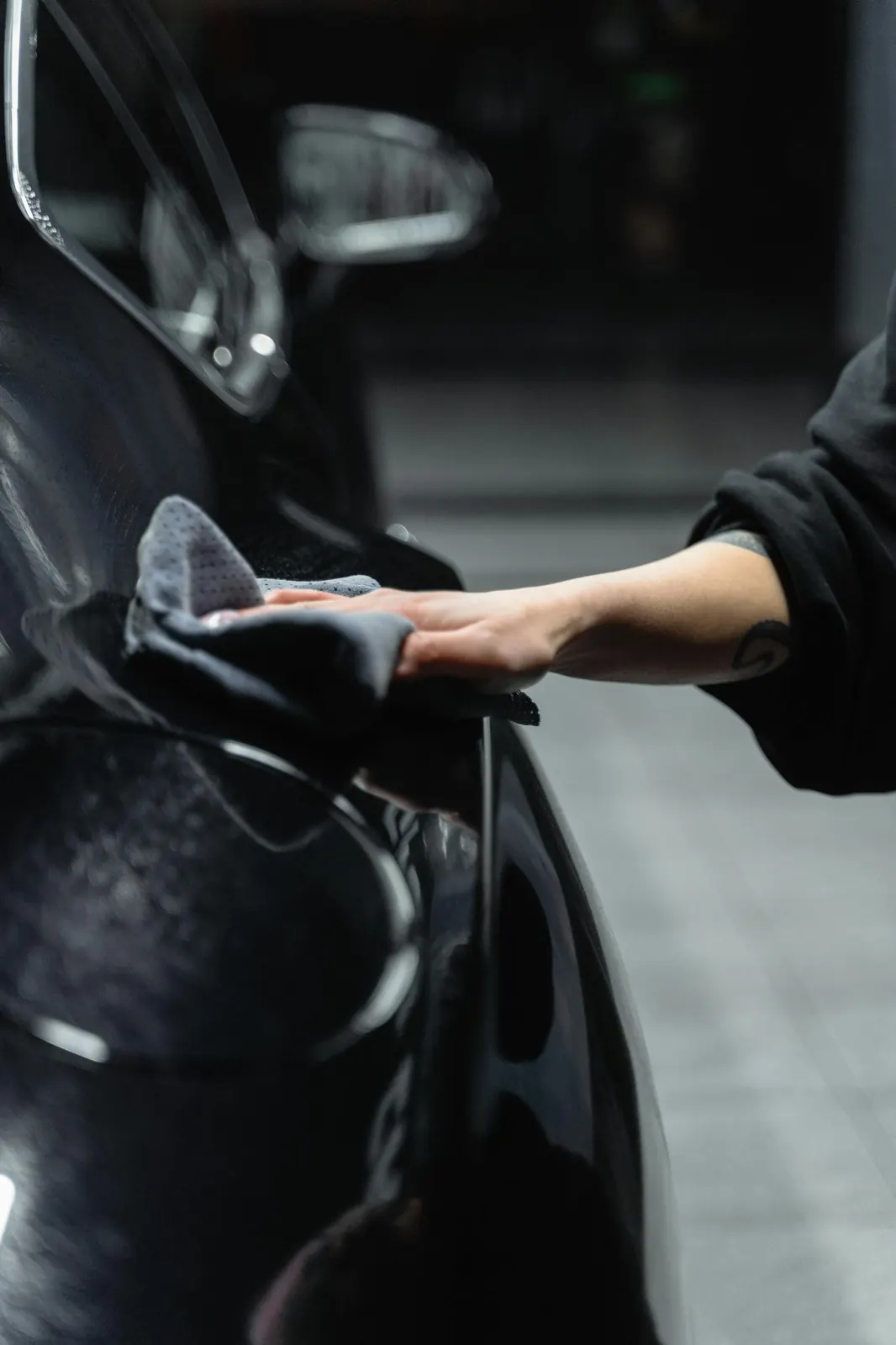 Detailer wiping a vehicle with a clean microfiber cloth